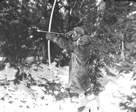 Homme innu non identifi� de la r�gion de Voisey's Bay et Davis Inlet, dans le Nord du Labrador, chassant la perdrix avec un arc et des fl�ches (photo Peary-MacMillan Arctic Museum).